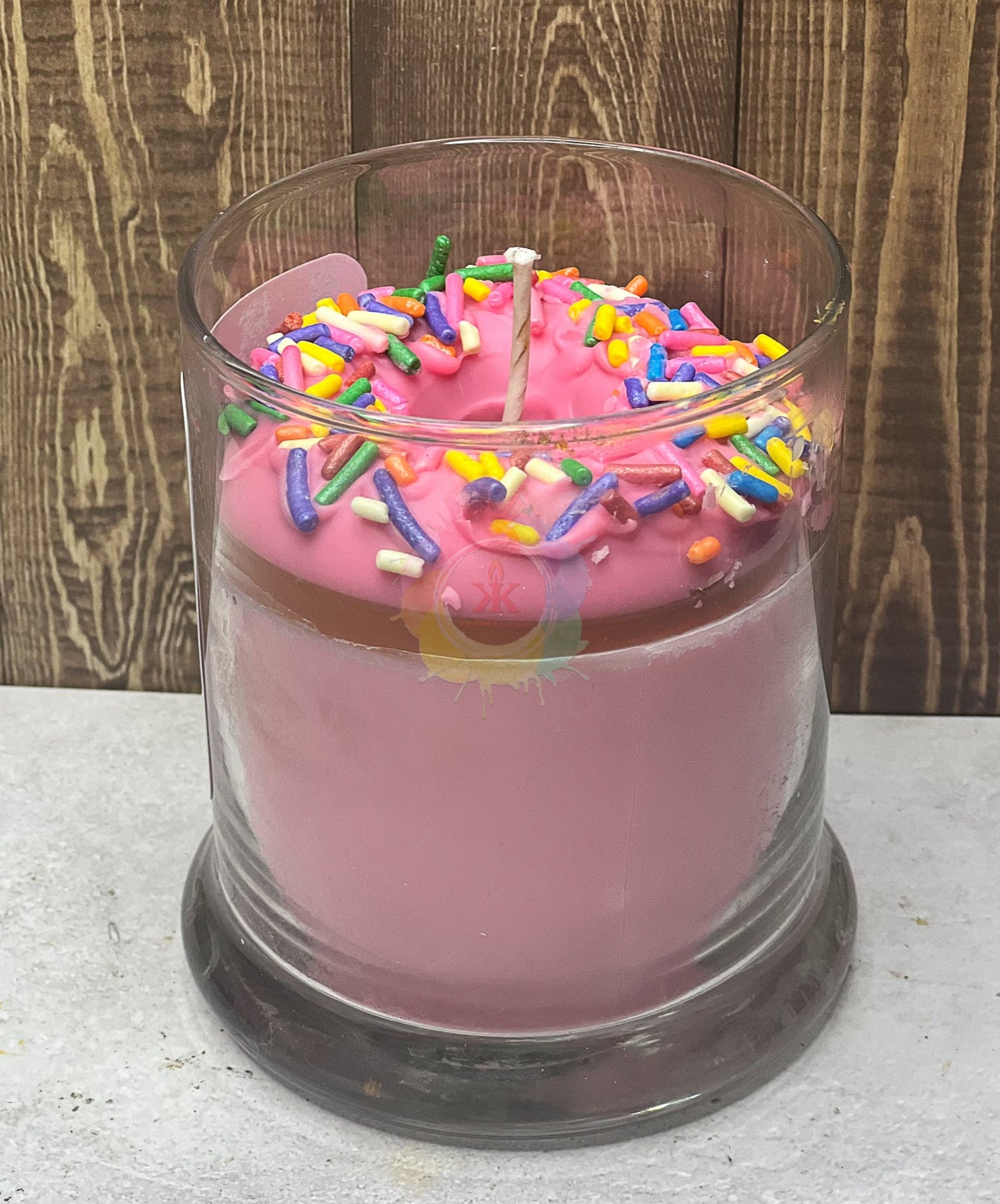 Jar glass candle. Wax donut with sprinkles in the middle of the glass. 