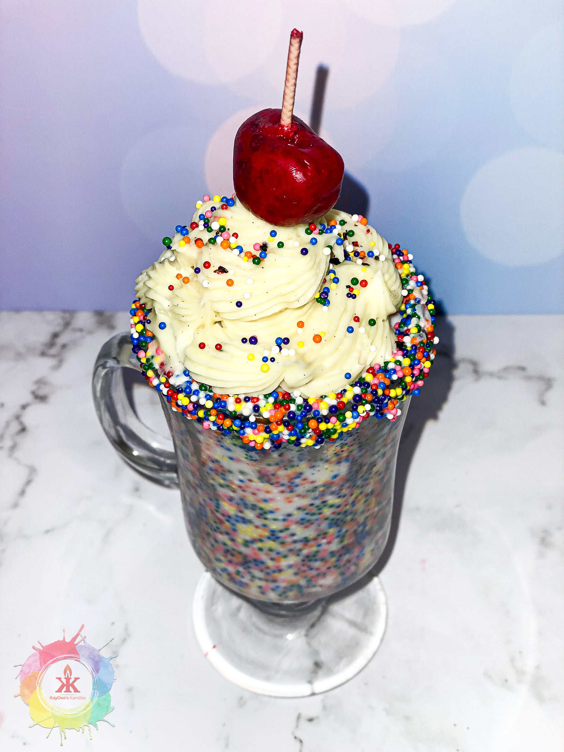 Photo of candle resembling a birthday cake milkshake with cherry on top.